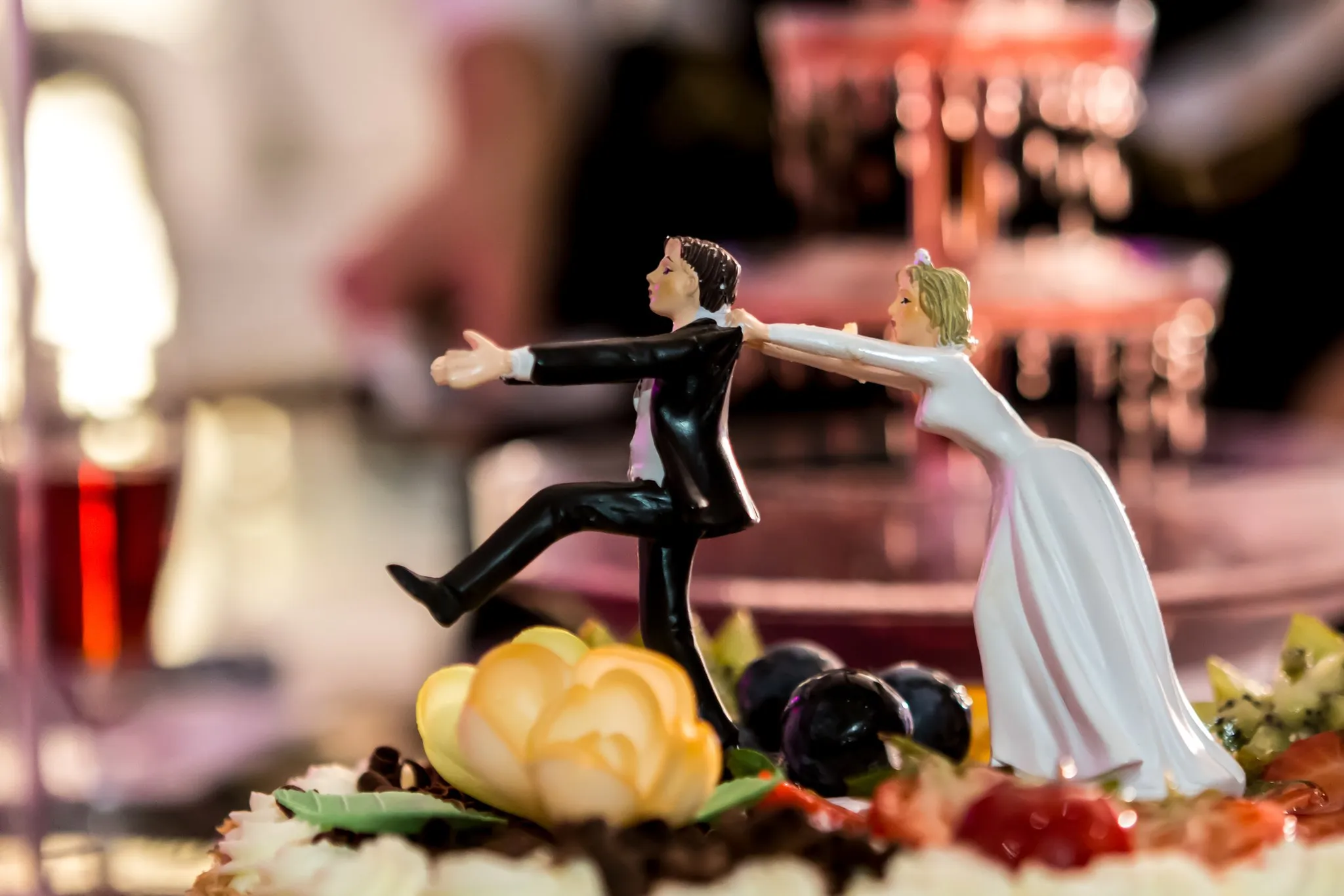 Bride and groom cake toppers on a fruit-decorated wedding cake